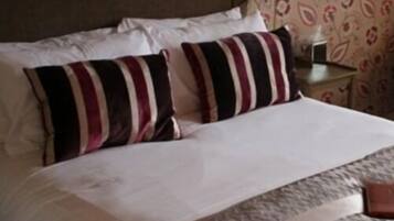 Una cama bien hecha con almohadones a rayas y una colcha blanca.