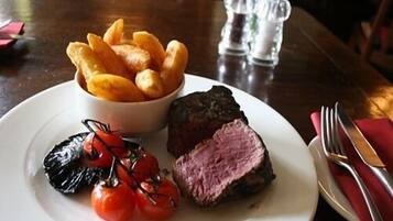 A plate with steak, roasted tomatoes, and fries.