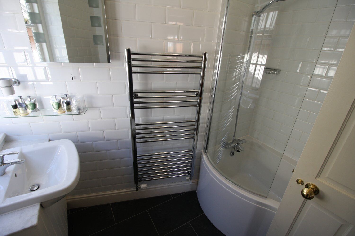 A bathroom with a white sink, a glass shower enclosure, and a towel rack.