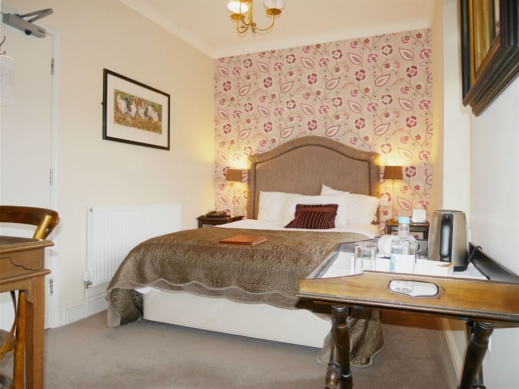 A bedroom with a bed, bedside table, lamp, and a framed picture on the wall.