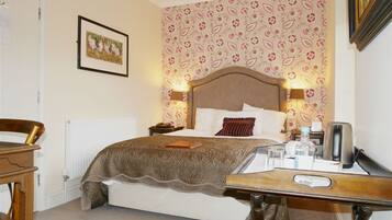 A bedroom with a bed, bedside table, lamp, and a framed picture on the wall.