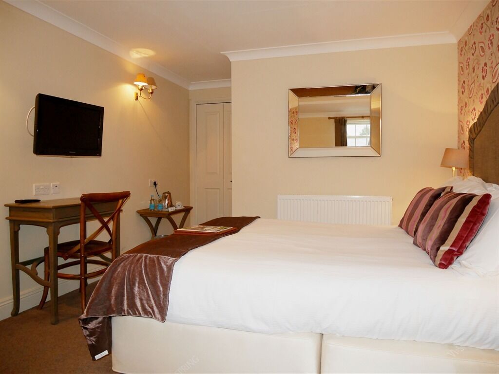 A hotel room with a bed, a desk, a chair, a television, and a mirror.