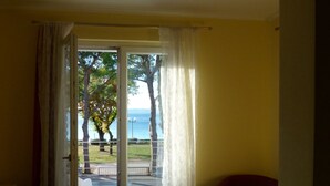 Een kamer met uitzicht op een park en de zee, door een schuifglazen deur.