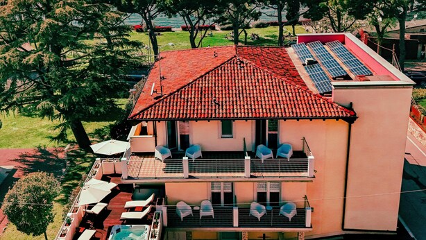 Een tweelaags huis met een rode dakbedekking, een balkon met buitenmeubels en een zwembad.