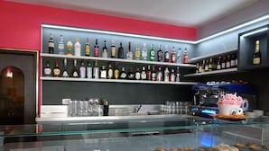Een bar met drankflessen op de planken, een vitrine met gebak en een koffieapparaat.