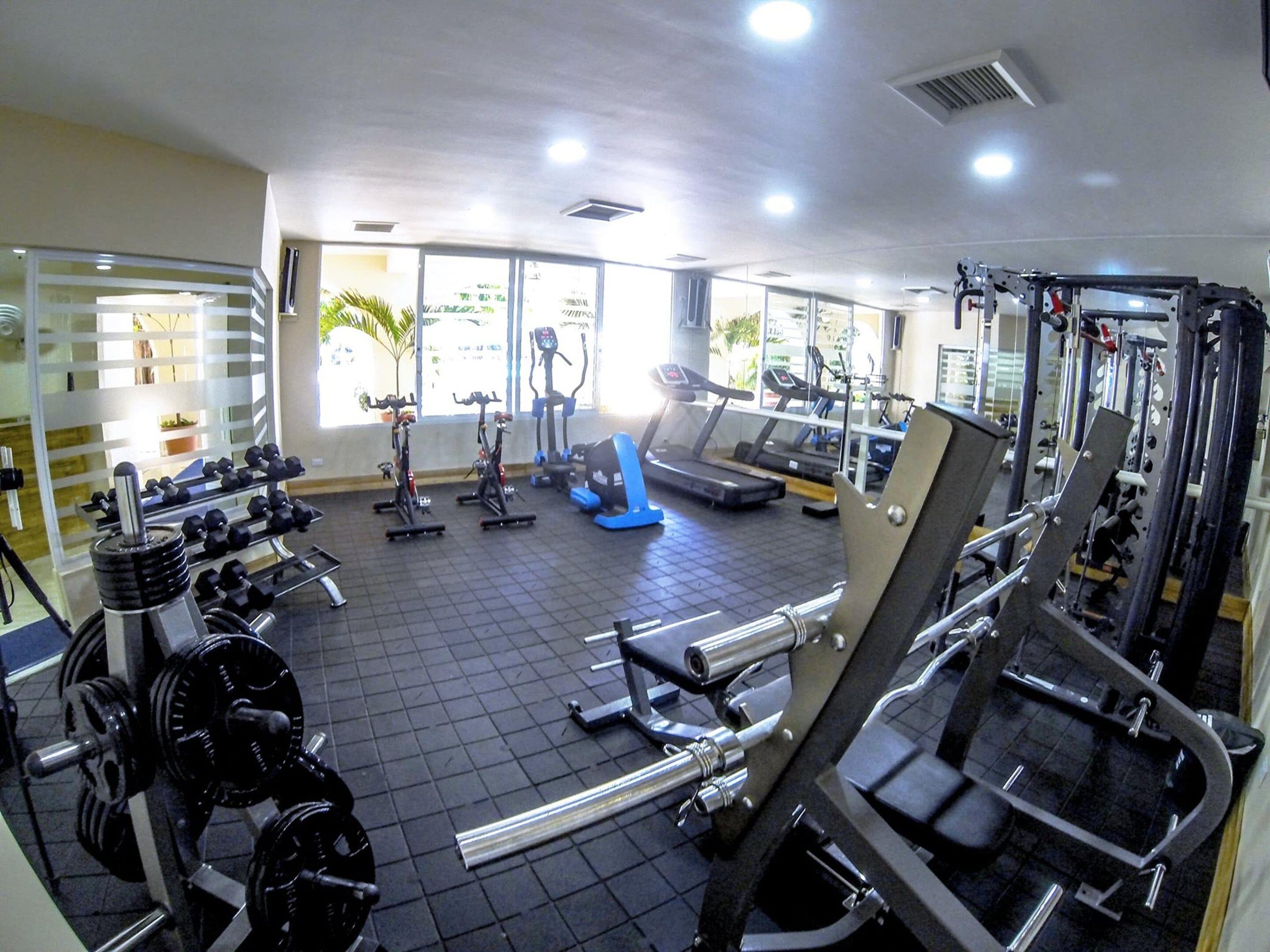 A gym with various exercise equipment, including treadmills, ellipticals, and weight machines.