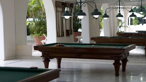 A pool table in a room with white walls and a tiled floor, surrounded by potted plants and a wooden bench. - Hotel Tocarema (Girardot)