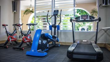 Un gimnasio con bicicletas estáticas, una máquina elíptica y una cinta de correr.