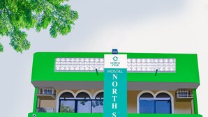 Un immeuble de deux étages avec une façade verte, une enseigne indiquant « HOSTAL NORTHSTAR » et une entrée fermée par un portail.