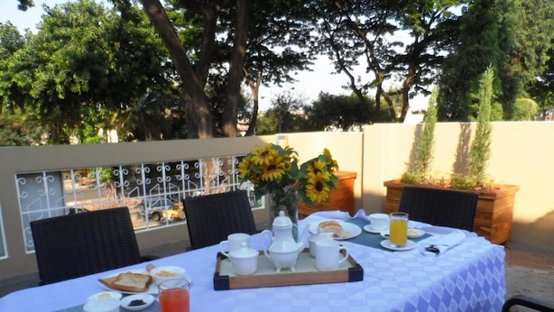 Un espace de restauration en plein air avec une table dressée pour le petit-déjeuner, comprenant du pain, des œufs et du jus de fruits.
