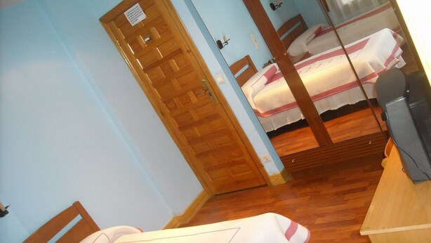 Une chambre avec deux lits, des meubles en bois et un téléviseur.