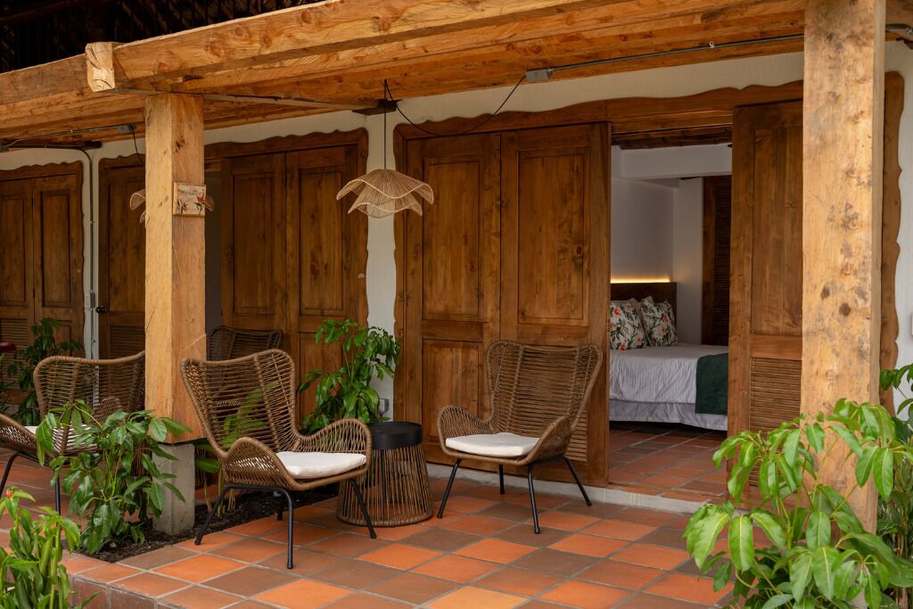 A wooden pergola with wicker furniture and potted plants.