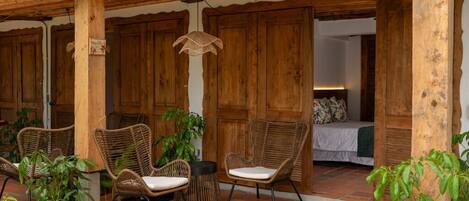 A wooden pergola with wicker furniture and potted plants.