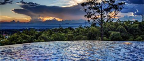 A pool with a view of a forest and mountains.