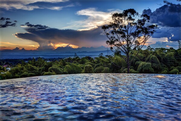 A pool with a view of a forest and mountains.