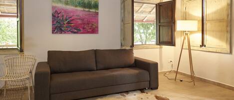 A living room with a sofa, a chair, a lamp, and a painting on the wall.