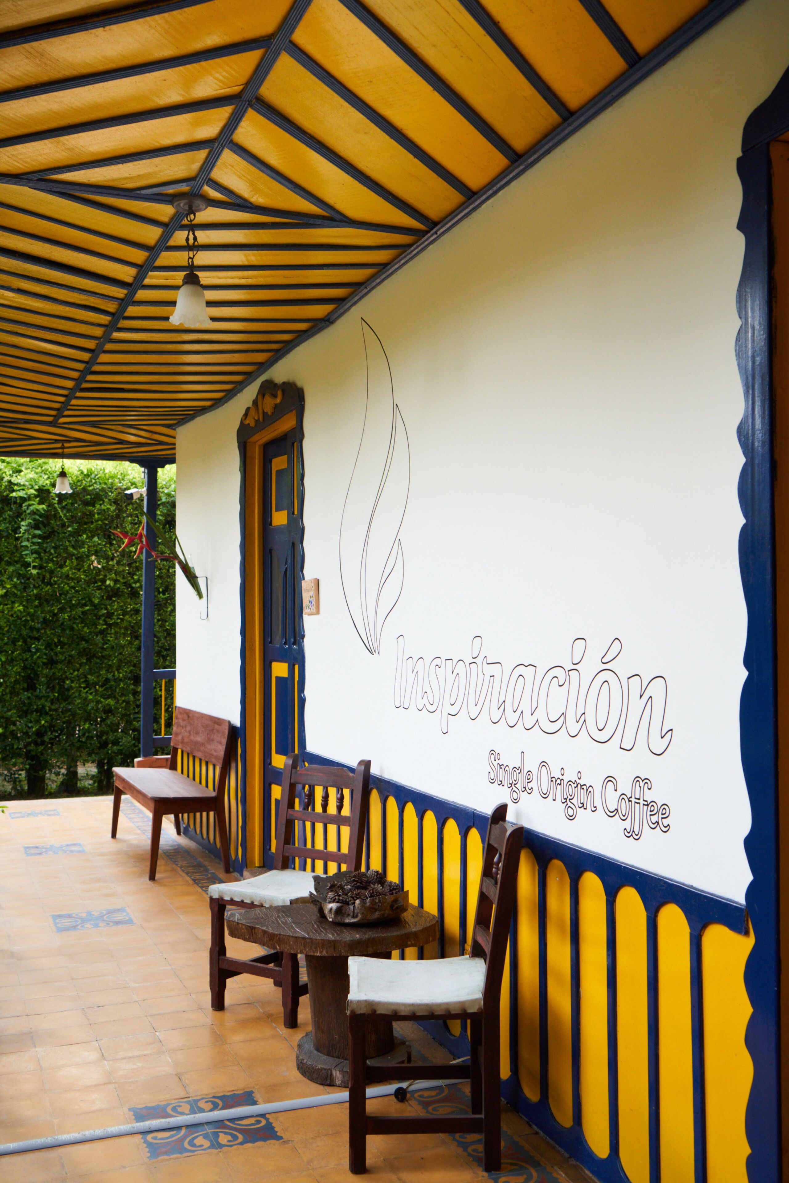 An outdoor seating area with wooden furniture, a table, and a wall with a logo and text.