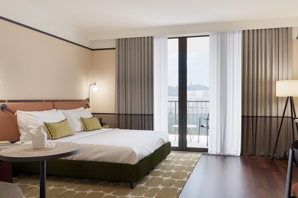 A hotel room with a bed, a desk, a chair, a TV, and a balcony with curtains.