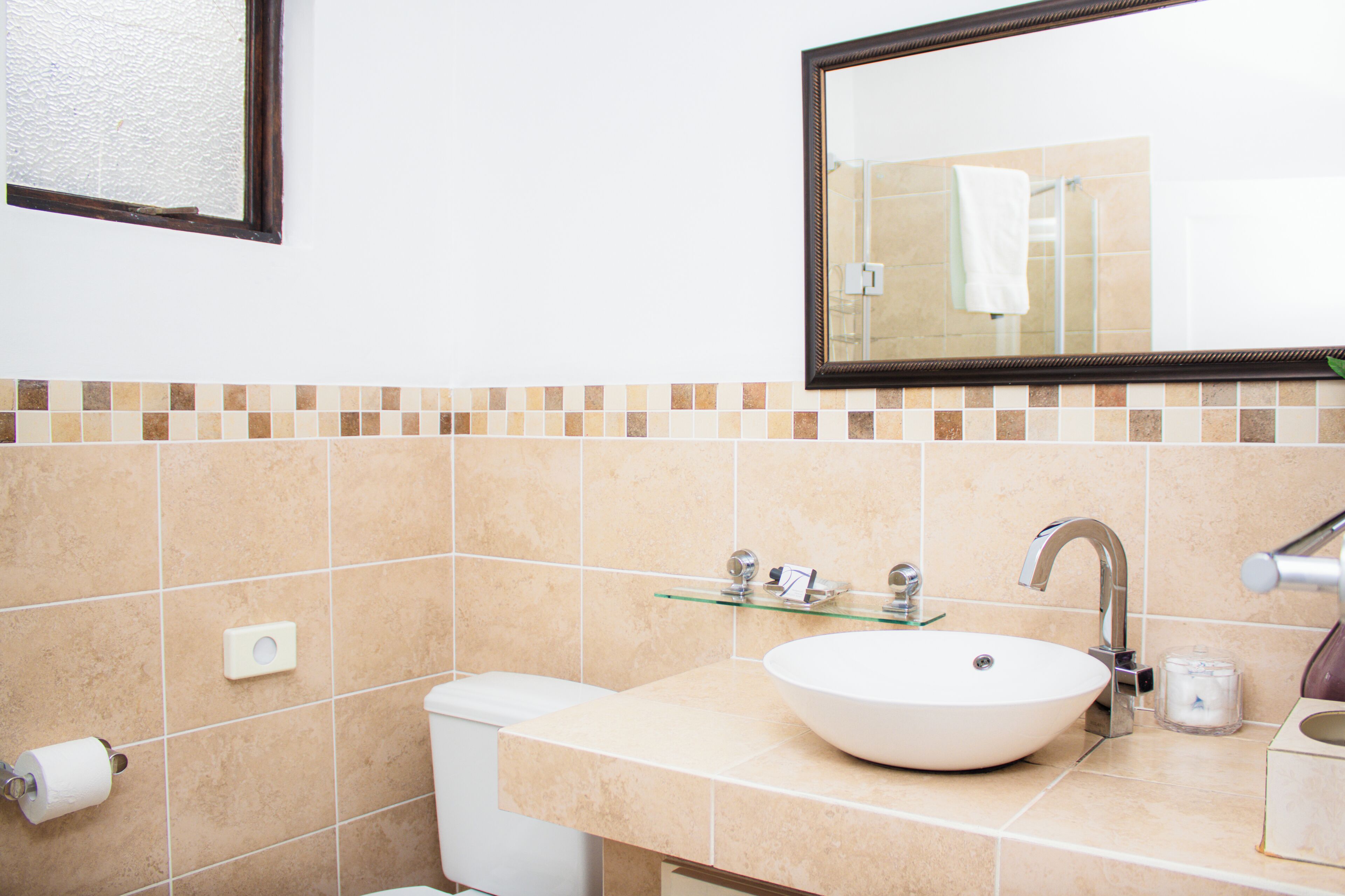 Un baño con un lavamanos blanco, un espejo y un inodoro.