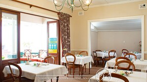 Un comedor con mesas dispuestas para el servicio, una araña y un tablón de anuncios.