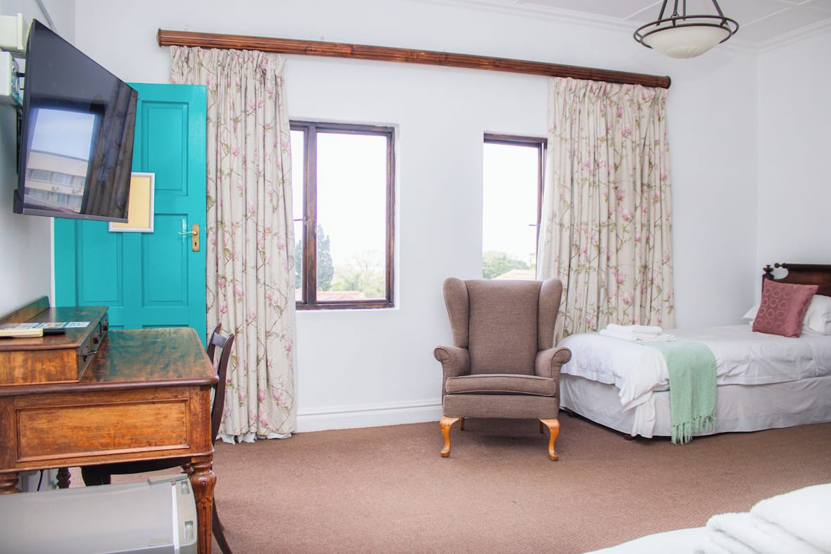 A bedroom with a bed, a chair, a desk, and a television.