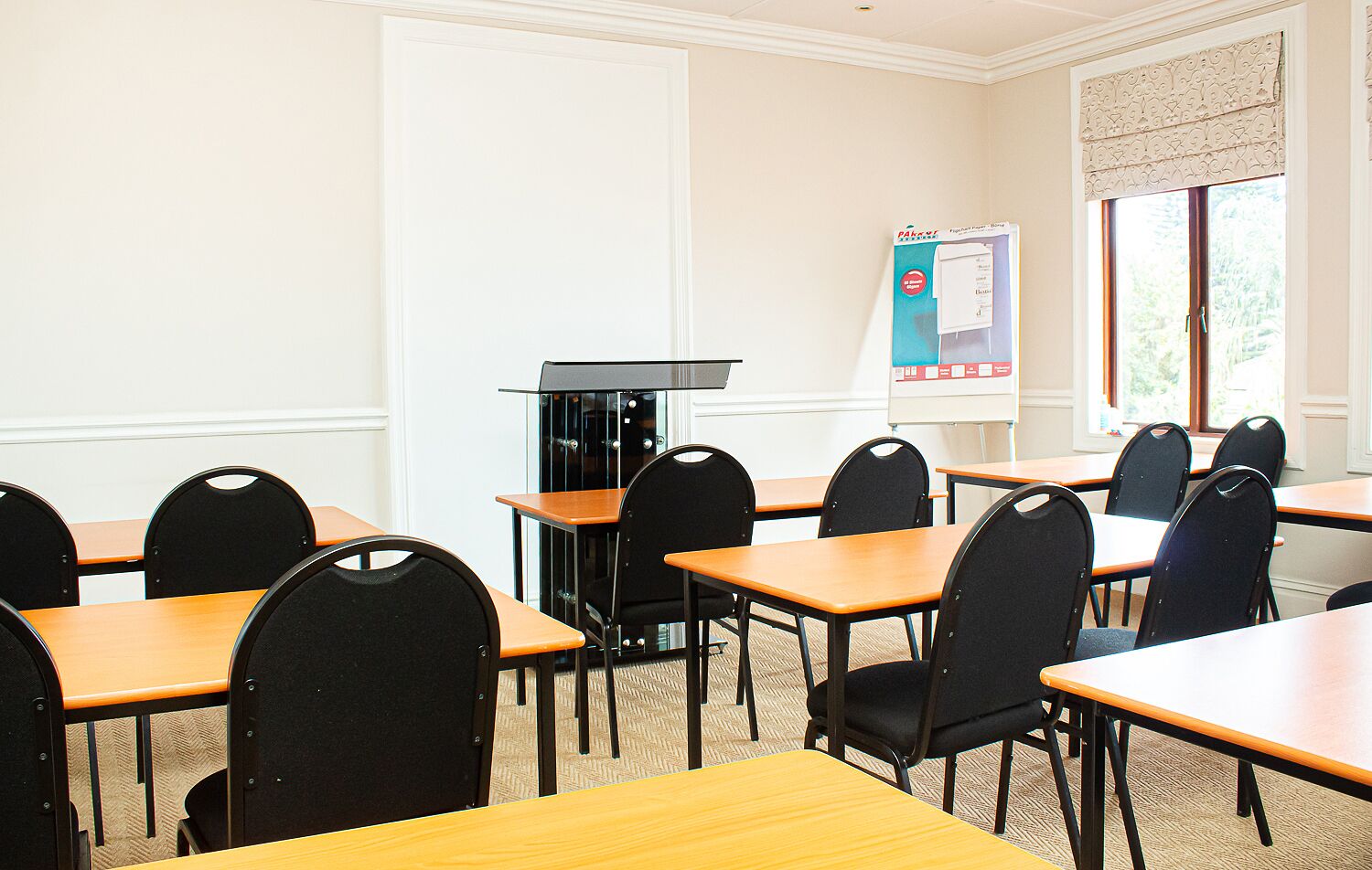 A conference room with multiple tables and chairs, a whiteboard, and a window with blinds.