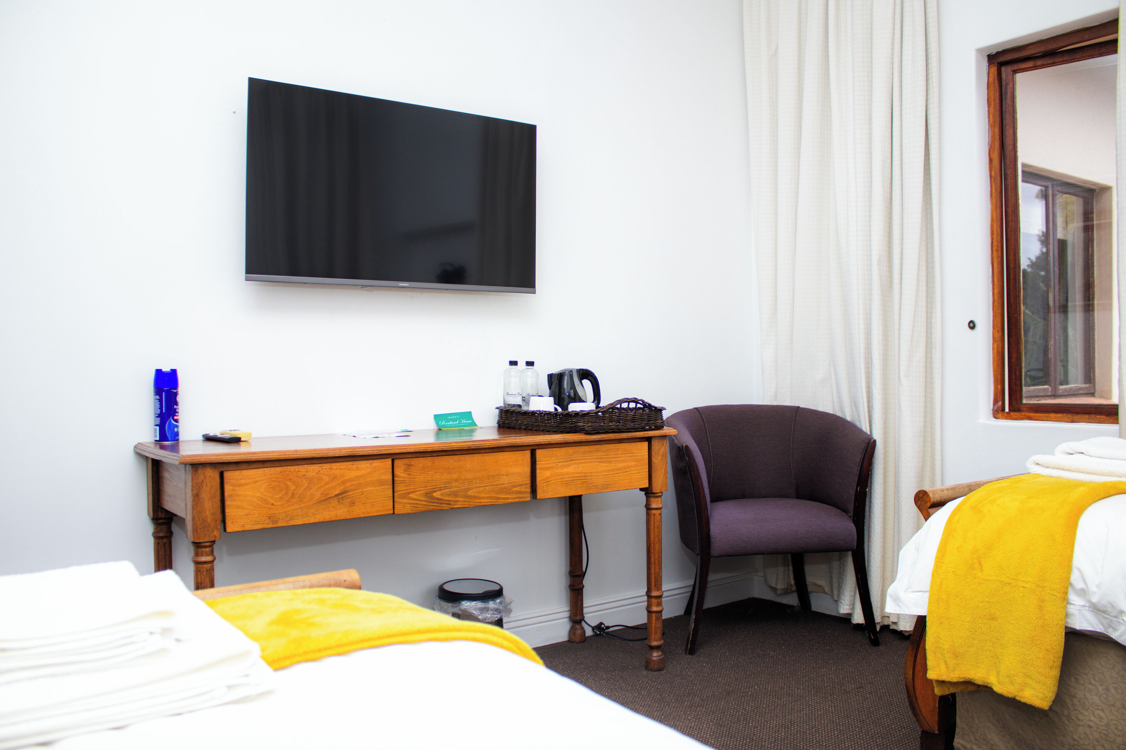 Una habitación de hotel con una cama, un escritorio con televisor, una silla y una ventana.