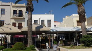 A street with palm trees, outdoor seating, and buildings with balconies. - Sea Front Old Town (Rethymno)
