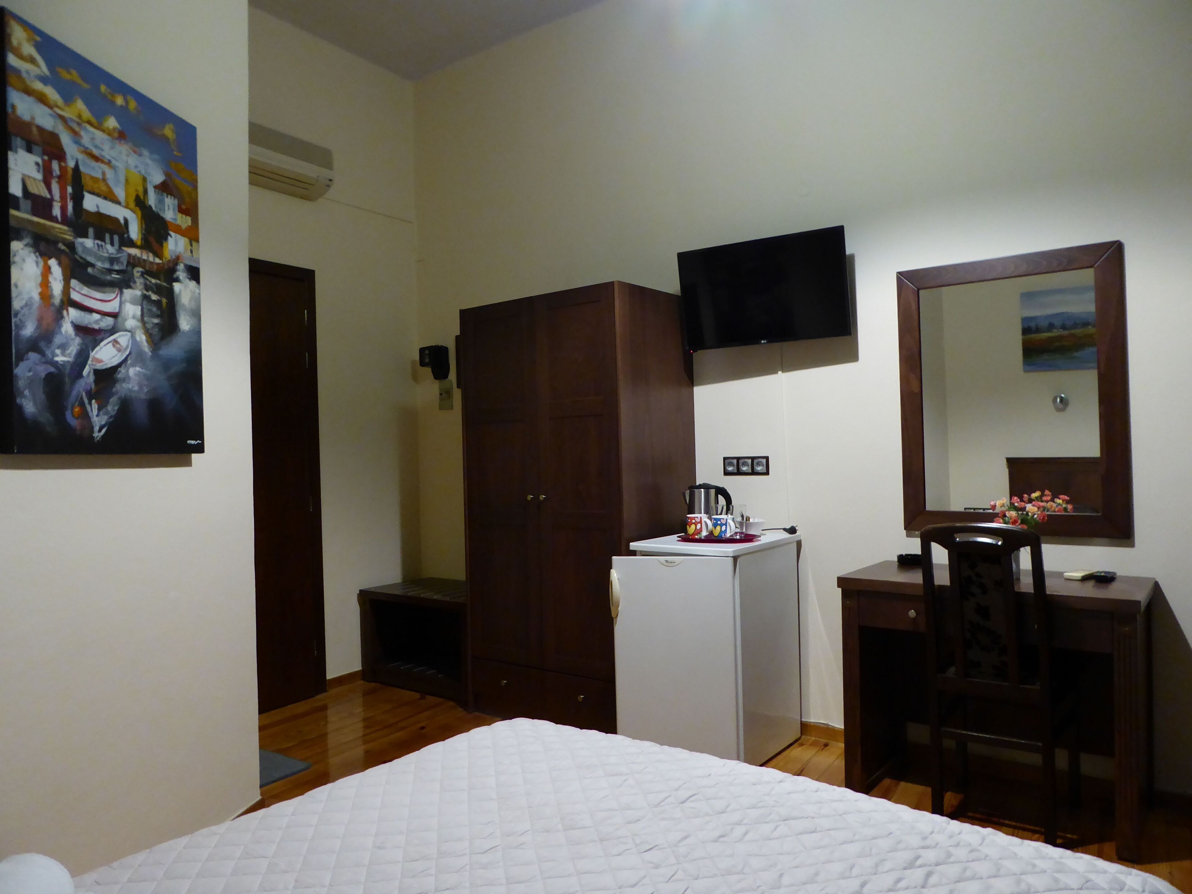 Une chambre à coucher comprenant un lit, une armoire, un bureau avec une chaise, une télévision et un tableau accroché au mur.