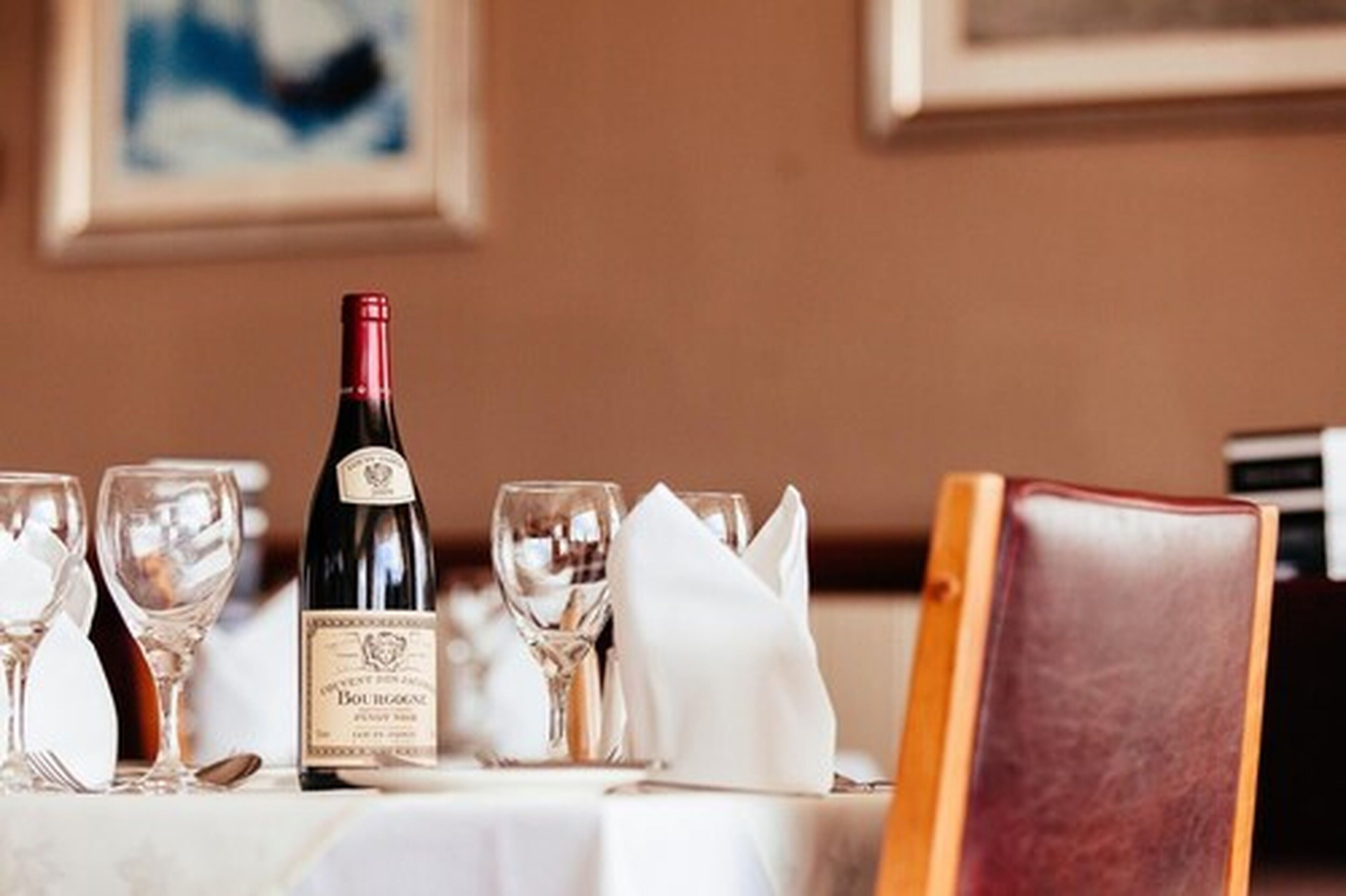 A table set with wine glasses, a bottle of wine, and a folded napkin, suggesting a dining setting.