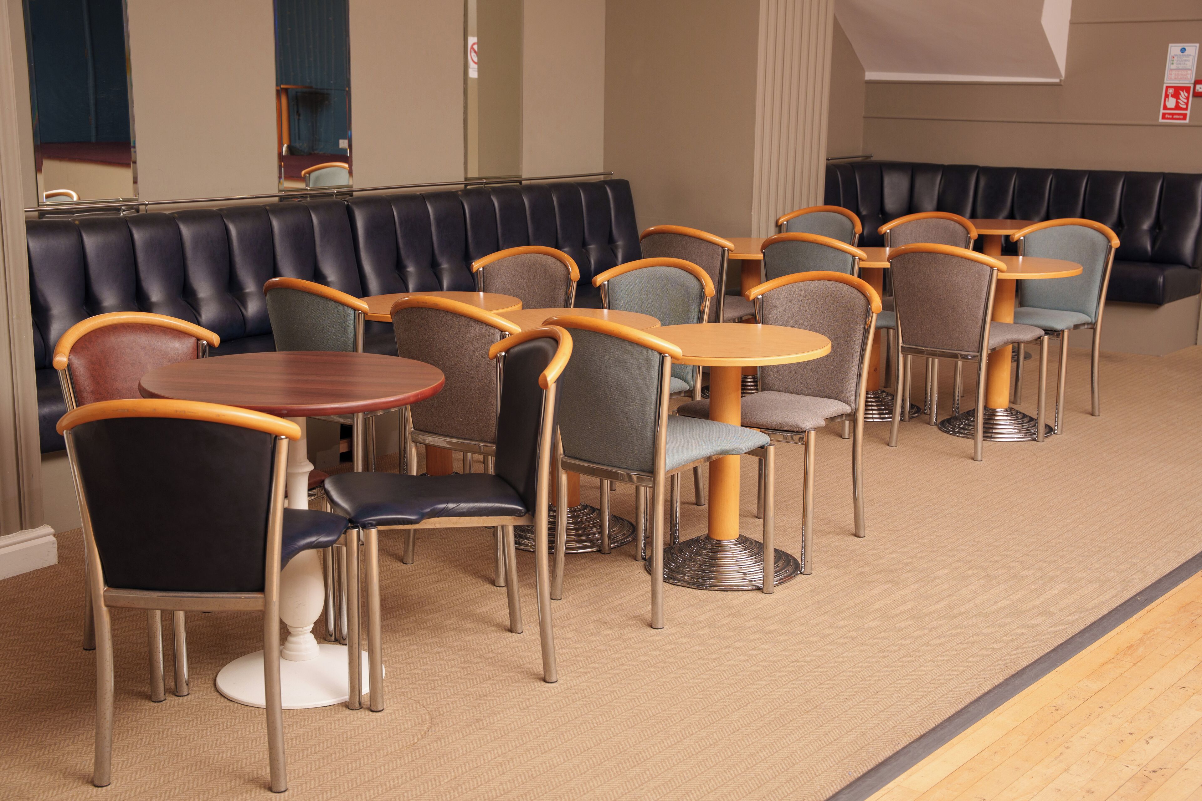 A restaurant with booths and tables, carpeted floor, and a mirror on the wall.