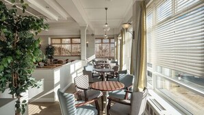 A spacious indoor area with multiple seating arrangements, large windows, and a potted plant. - Trouville Hotel by Compass Hospitality (Sandown)