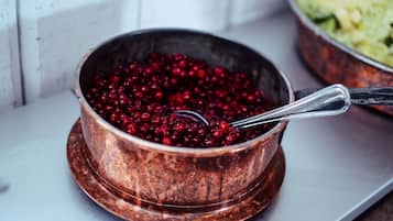 A copper bowl filled with red berries on a white surface.