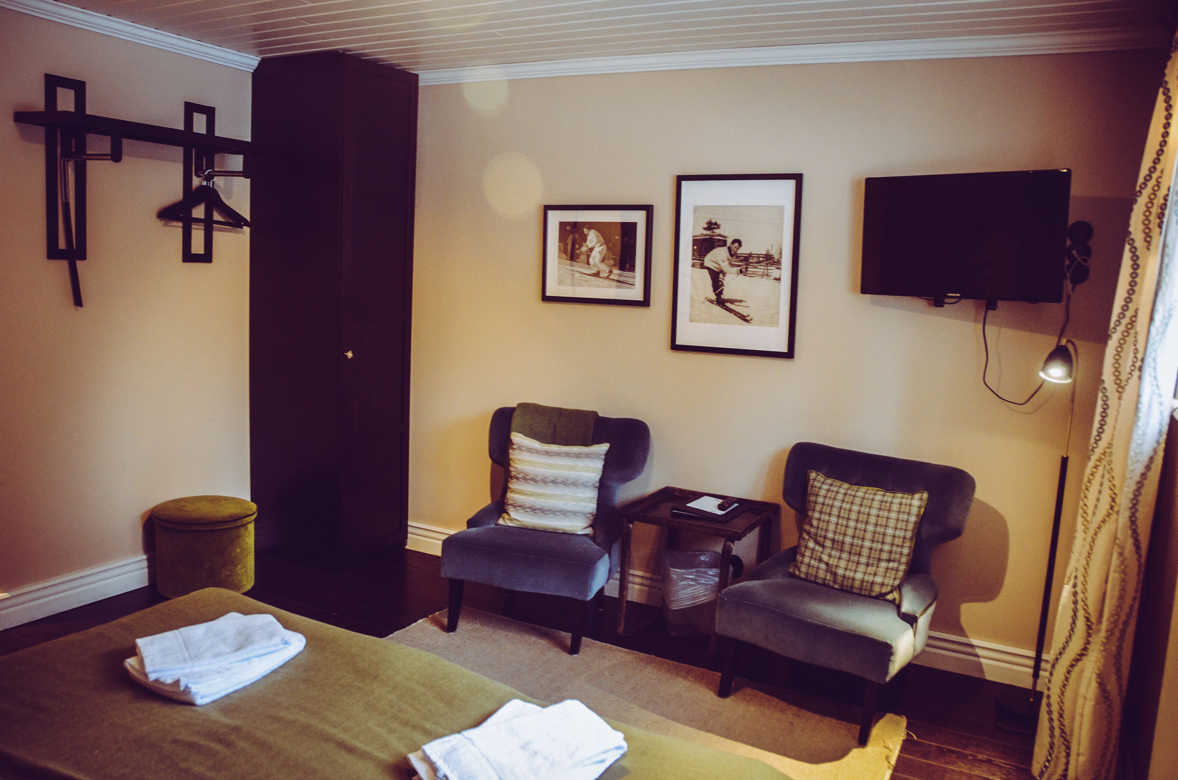 Una habitación con dos sillones, una mesita, un televisor y una cruz en la pared.