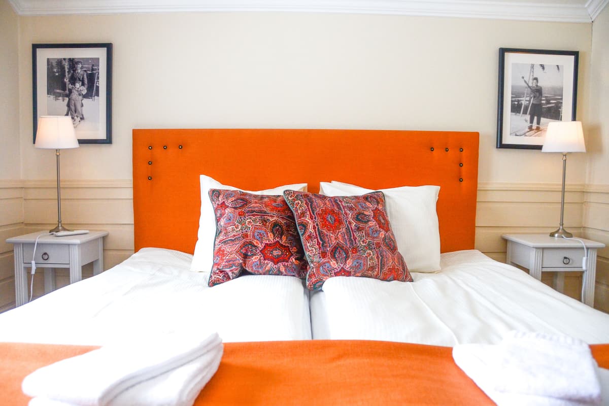 Ein Hotelzimmer mit einem großen Bett, zwei Nachttischen und einem leuchtend orangefarbenen Kopfteil.