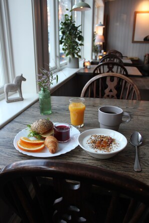Enjoy a delicious breakfast with a variety of options, including pastries, sandwiches, and cereal, served in a cozy room with a window and a plant.