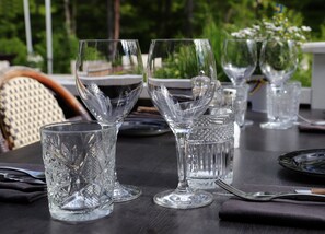 Enjoy dining al fresco with a beautifully set table featuring fine glassware, elegant cutlery, and a serene garden view.