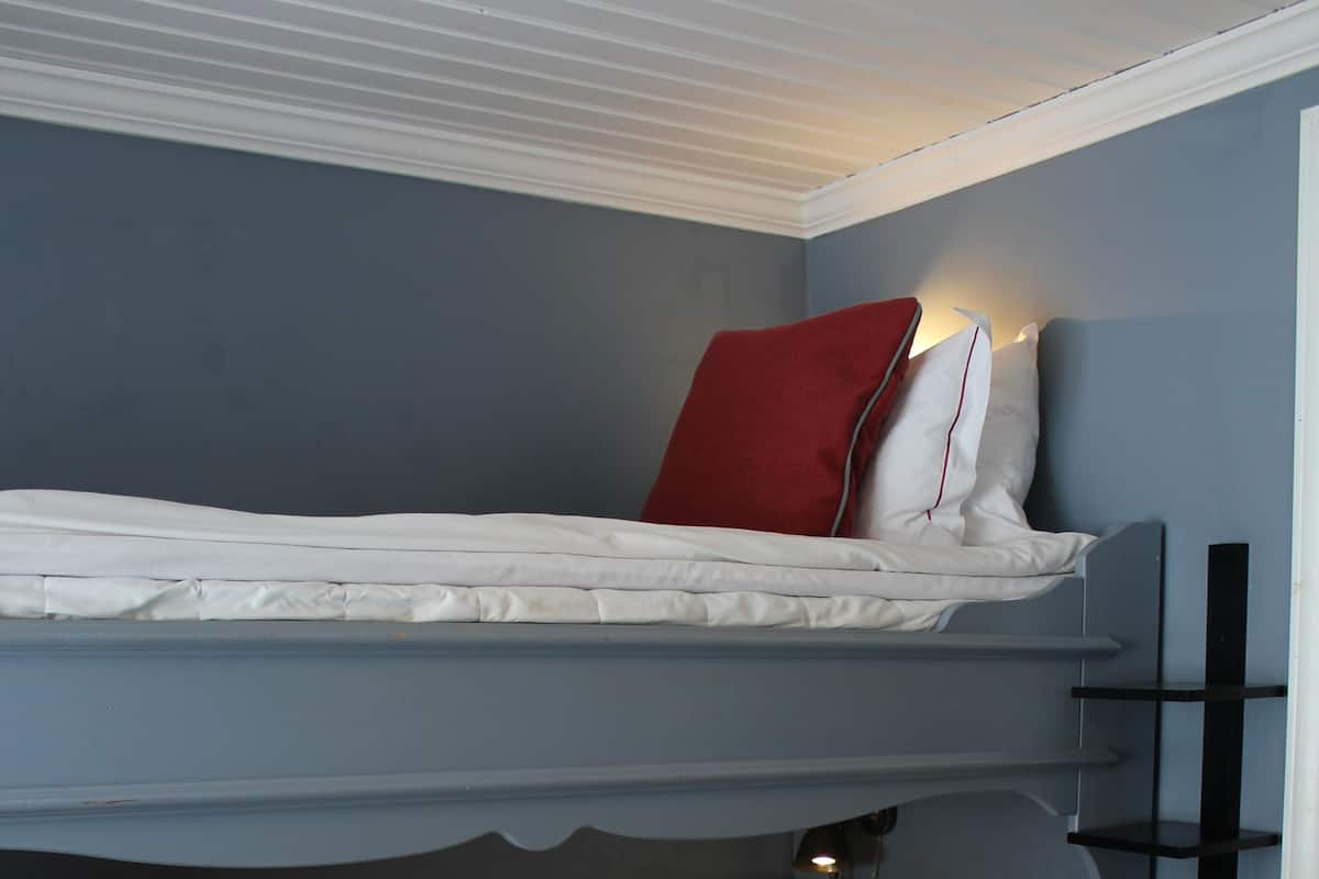Ein Stockbett mit zwei Etagen, jeweils mit Kissen und Decke.