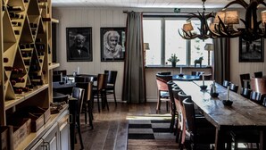 Comedor con una larga mesa de madera, sillas, una estantería para vinos y una araña.
