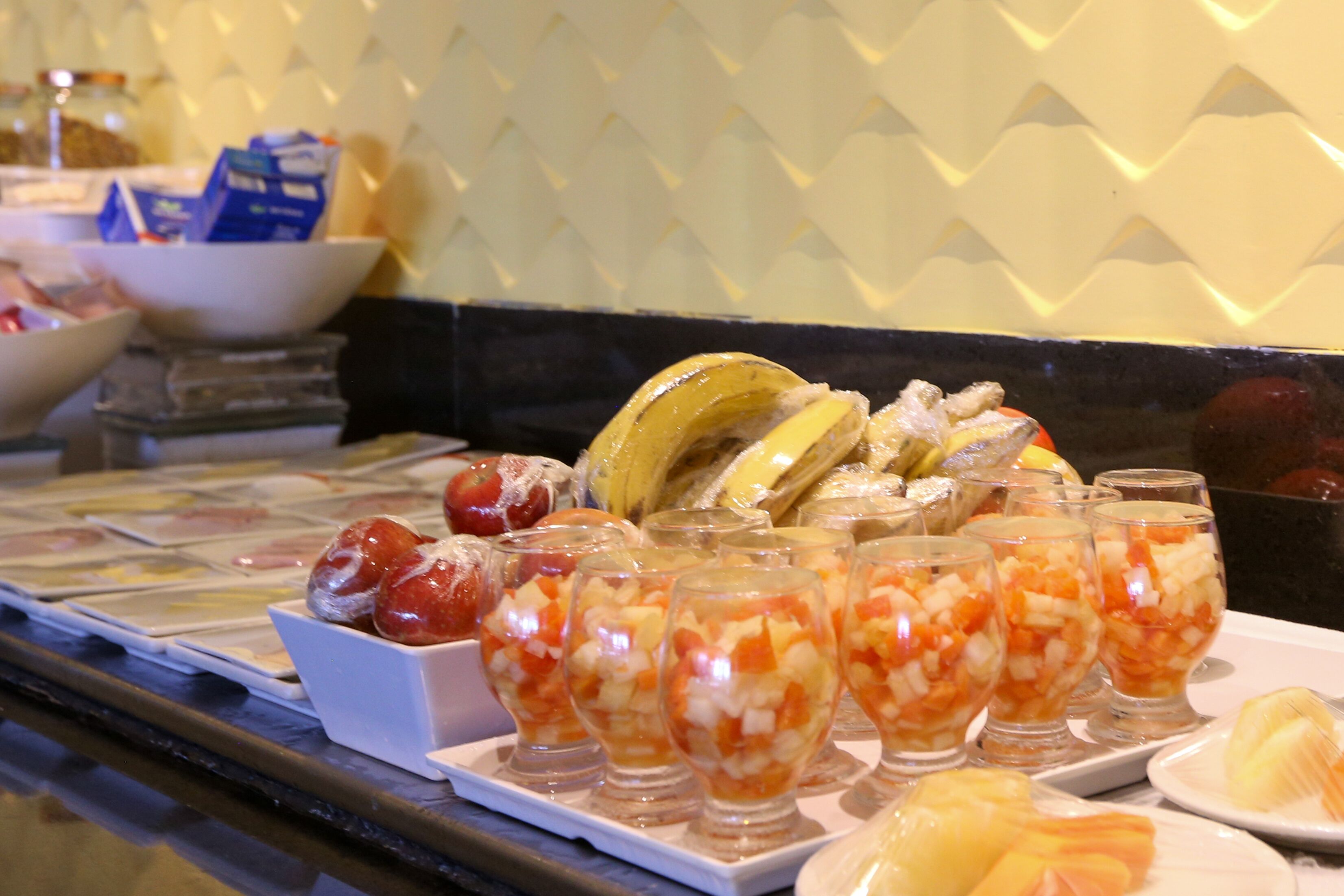 Un bufé con diferentes opciones de comida, incluyendo frutas, verduras y un tazón de cereales.