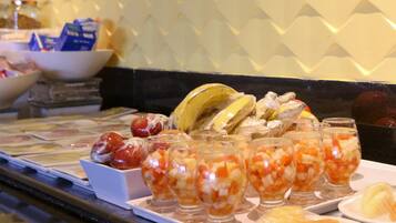 Un bufé con diferentes opciones de comida, incluyendo frutas, verduras y un tazón de cereales.