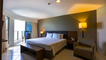 Quarto de hotel com uma cama grande, uma escrivaninha, uma cadeira e vista para o exterior.
