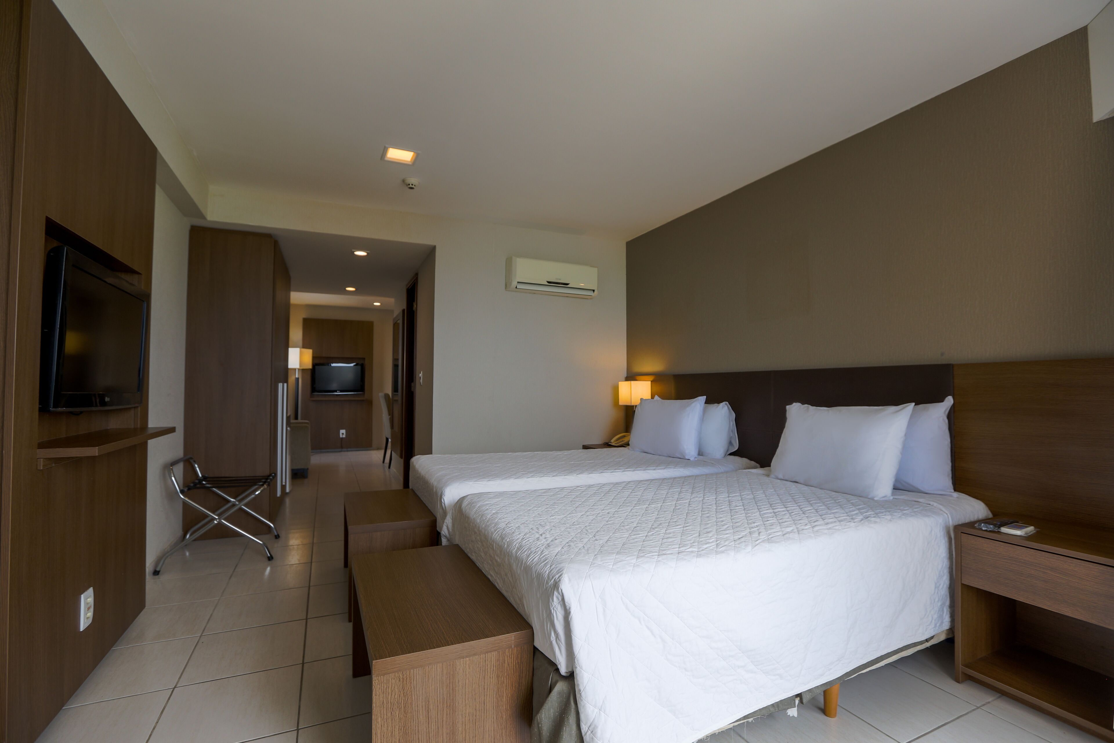 Une chambre d’hôtel avec deux lits, une télévision, un bureau et une lampe.