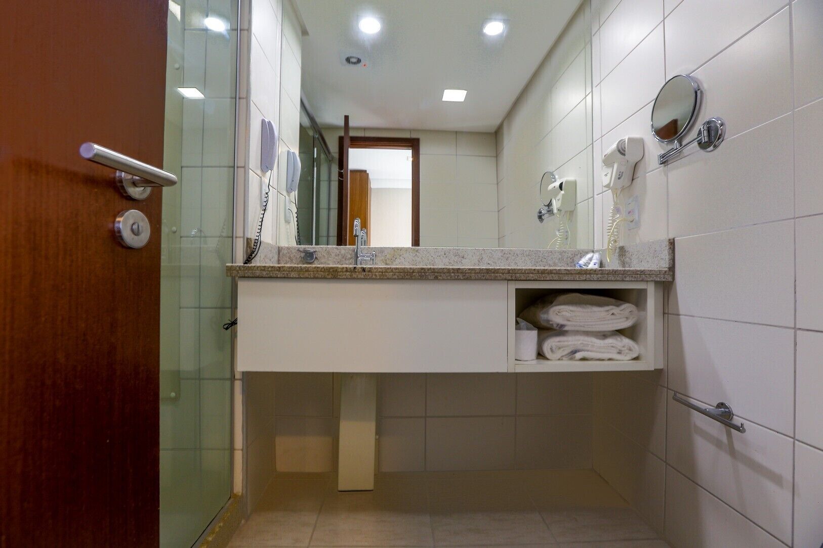 Un baño con lavamanos, espejo, toallero y una puerta con picaporte.