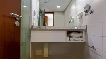Un baño con lavamanos, espejo, toallero y una puerta con picaporte.