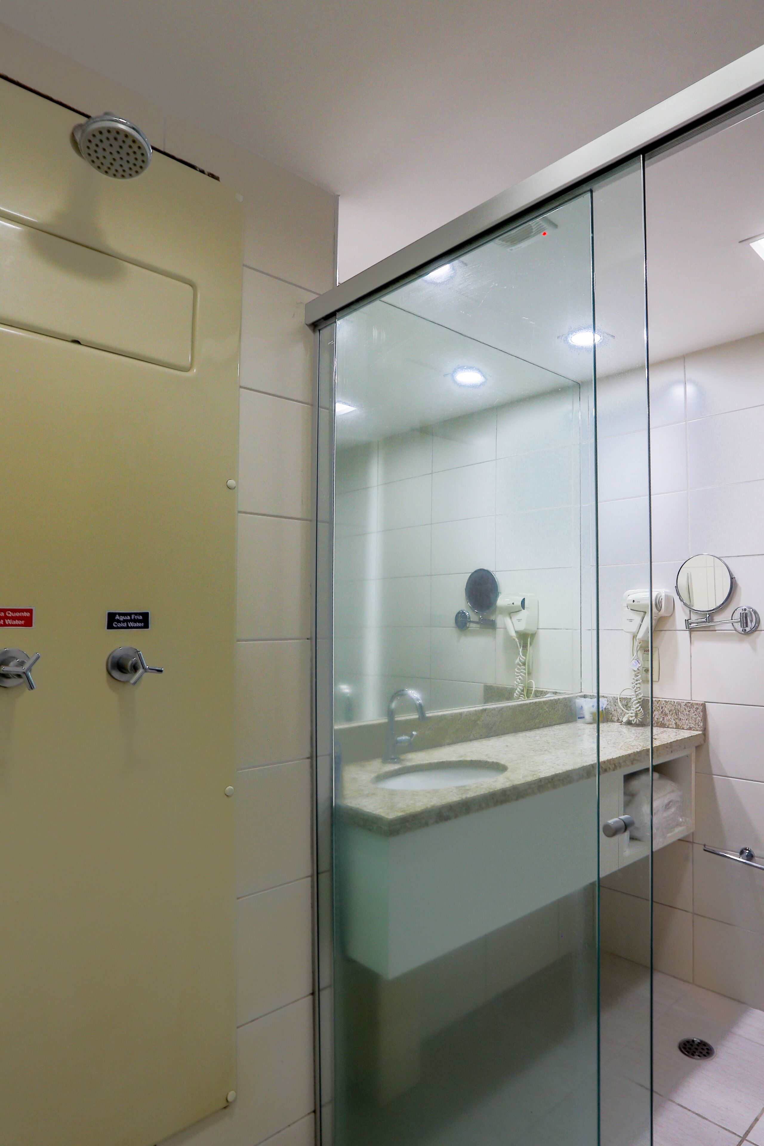 Un baño con cabina de ducha de vidrio, un lavabo con espejo y un perchero para toallas.