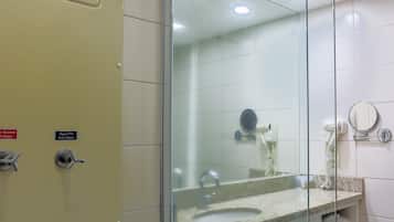 Un baño con cabina de ducha de vidrio, un lavabo con espejo y un perchero para toallas.