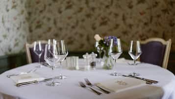 A round dining table set with multiple wine glasses, cutlery, and a folded menu.