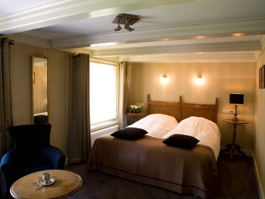 Ein Hotelzimmer mit einem Bett, einem Sessel, einem Tisch und einem Spiegel.