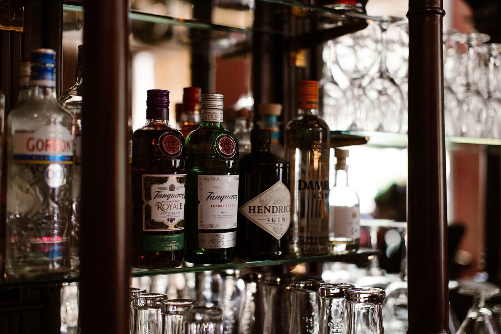 A bar shelf with various bottles of gin and other spirits.